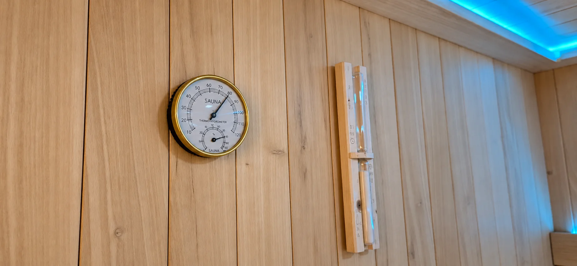 Saunathermometer op 80 graden en een zandloper aan de houten wand